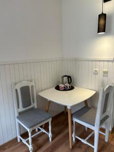 a table with two chairs and a tea kettle on it at Cicha Zatoka in Mikołajki