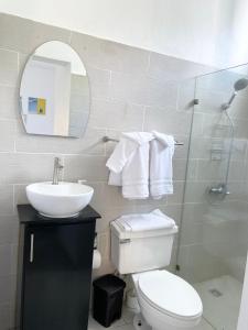 a bathroom with a toilet and a sink and a mirror at The White Rock Hotel B&B in Los Conucos