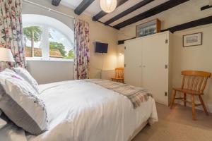 a bedroom with a white bed and a window at The Barn in Burnham Market