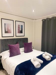 a bedroom with a bed with purple and white towels on it at Stylish En Suite double room Kensington in London