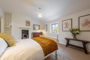 a bedroom with a large white bed and a table at Chiffchaff Cottage in West Raynham