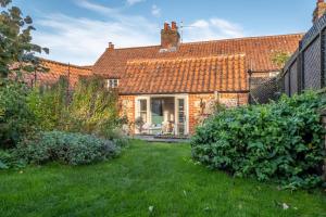 an old brick house with a green yard at Chiffchaff Cottage in West Raynham