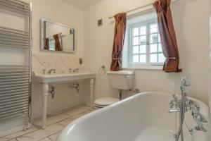 a bathroom with a tub and a sink and a toilet at 2 Dix Cottages in Thornham +37 photos