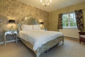 a bedroom with a bed and two tables and a chandelier at 2 Dix Cottages in Thornham