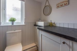 a bathroom with a toilet and a sink and a window at Kipling House 8 in Wells next the Sea +30 photos
