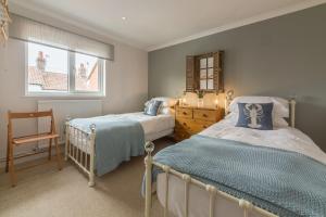a bedroom with two beds and a chair in it at Kipling House 8 in Wells next the Sea