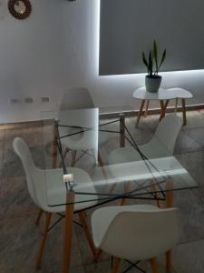 una mesa de cristal con sillas blancas y una maceta en Orfila Apart 4 en Mendoza
