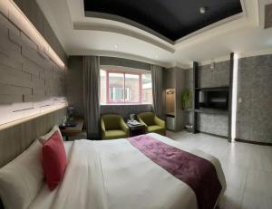 ein Hotelzimmer mit einem Bett und zwei Stühlen in der Unterkunft Alia Motel in Bezirk Sanxia