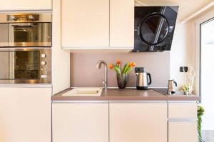 a kitchen with white cabinets and a sink at Fuga romantica - Mansarda chic con box privato & mare a 150m in Loano