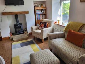 a living room with two chairs and a stove at Cosy cottage, Pateley Bridge in Pateley Bridge