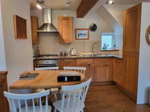 eine Küche mit einem Holztisch und weißen Stühlen in der Unterkunft Cosy cottage, Pateley Bridge in Pateley Bridge