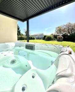uma banheira de hidromassagem no quintal de uma casa em L'Eden chambre d'hôtes avec jacuzzi et massages em Saint-Aubin-la-Plaine