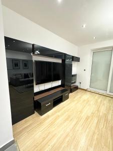 a living room with a large flat screen tv at Retreat to a Stylish Ensuite in London in London