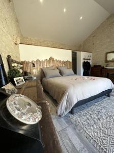 um quarto com uma cama grande e uma mesa em L'Eden chambre d'hôtes avec jacuzzi et massages em Saint-Aubin-la-Plaine