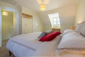 a large white bed with two red pillows on it at Taureans in Wells next the Sea