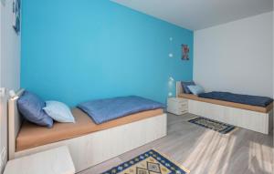 two beds in a room with a blue wall at Awesome Home In Donji Prolozac With Wifi in Donji Proložac