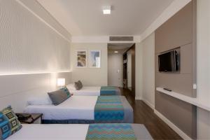 um quarto de hotel com duas camas e uma televisão em Monreale Plus Midtown Campinas em Campinas