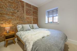 um quarto com uma cama e uma parede de tijolos em The Nurseries em Syderstone