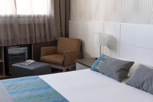 um quarto de hotel com uma cama e uma cadeira em Monreale Plus Midtown Campinas em Campinas