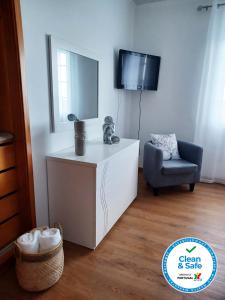a living room with a tv and a chair at Alves Nature Rooms in Arrifes