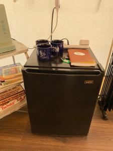 a black refrigerator with two cups and a laptop on it at Silver Spur Homestead Luxury Glamping -The Miner in Tombstone