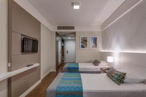 a hotel room with two beds and a tv at Monreale Plus Midtown Campinas in Campinas