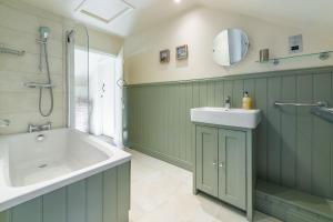 a bathroom with a tub and a sink and a mirror at Swift Cottage in Dersingham +21 photos