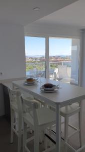 ein weißer Tisch mit Stühlen, Tellern und Gläsern darauf in der Unterkunft Apartamento con vistas en Gran Canet in Canet d'en Berenguer