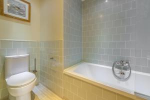 a bathroom with a toilet and a bath tub at Bettys Cottage in Brancaster