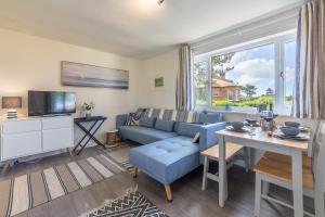 uma sala de estar com um sofá azul e uma mesa em Beach Retreat em Weybourne