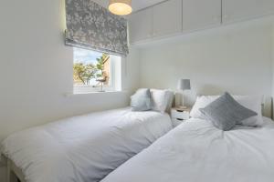 Duas camas num quarto branco com uma janela em Beach Retreat em Weybourne