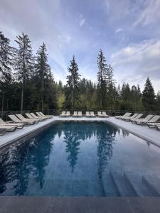 a large swimming pool with lounge chairs and trees at Girski Hotel&Spa in Bukovel