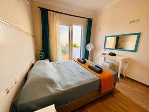 a bedroom with a bed with a mirror and a window at Goknar Knidos Oasis Nature Hotel in Datca