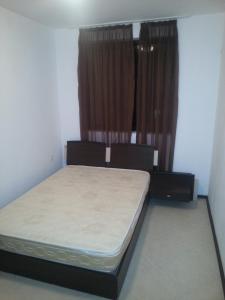 ein kleines Schlafzimmer mit einem Bett und Vorhängen in der Unterkunft Apartment Nova in Burgas City