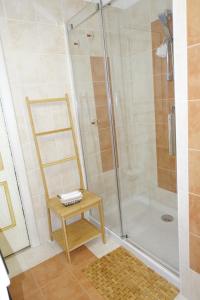 a bathroom with a shower with a chair and a stool at Little sea town apartment in La Ciaccia +17 photos