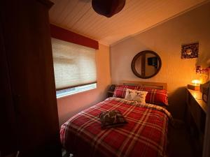 Ramintoul Lodge في Glendevon: غرفة نوم بسرير وبطانية حمراء ومرآة