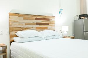 a bedroom with a white bed with a wooden headboard at Elegant House The Heart Of Flores in Flores