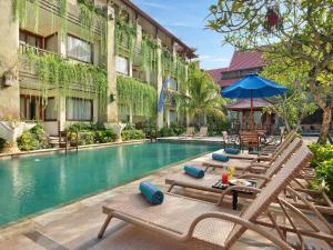 einen Pool mit Liegestühlen und ein Hotel in der Unterkunft The Grand Bali Nusa Dua in Nusa Dua