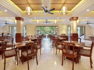 a restaurant with wooden tables and chairs and a ceiling at The Grand Bali Nusa Dua in Nusa Dua
