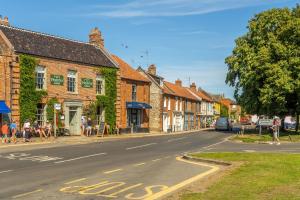 une rue dans une ville avec des gens assis sur le trottoir dans l'établissement Petts Cottage, à Burnham Market