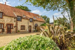 an old stone house with plants in front of it at Hideaway Barn 4 in Thornham
