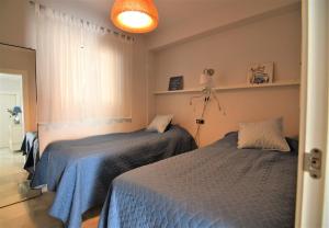 een slaapkamer met 2 bedden met blauwe lakens en een raam bij Edf. Fuentes C 2ºd - Eurosur in Nerja