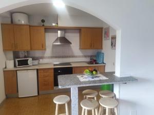 una cocina con armarios de madera y una barra con taburetes en Apartamentos turísticos Lemos, en O Pedrouzo