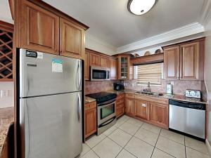 a kitchen with wooden cabinets and a stainless steel refrigerator at Villas on the Gulf #N1 in Pensacola Beach