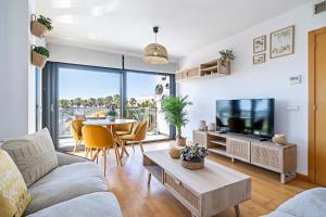 ein Wohnzimmer mit einer Couch, einem Fernseher und einem Tisch in der Unterkunft Apartamento El Castillo in Roquetas de Mar