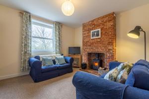 a living room with two blue couches and a fireplace at 2 Providence Place in Thornage