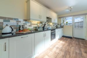 a kitchen with white cabinets and a wooden floor at 2 Providence Place in Thornage