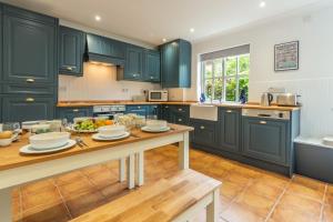 a kitchen with blue cabinets and a table with food on it at Diggers Rest in Burnham Market