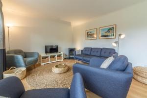 a living room with blue couches and a tv at Diggers Rest in Burnham Market