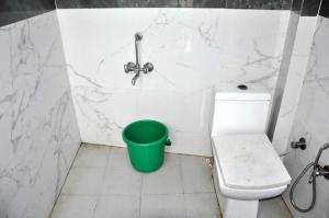 a bathroom with a toilet and a green bucket at OYO The Moonshine Hotel in Charkhi Dādri
